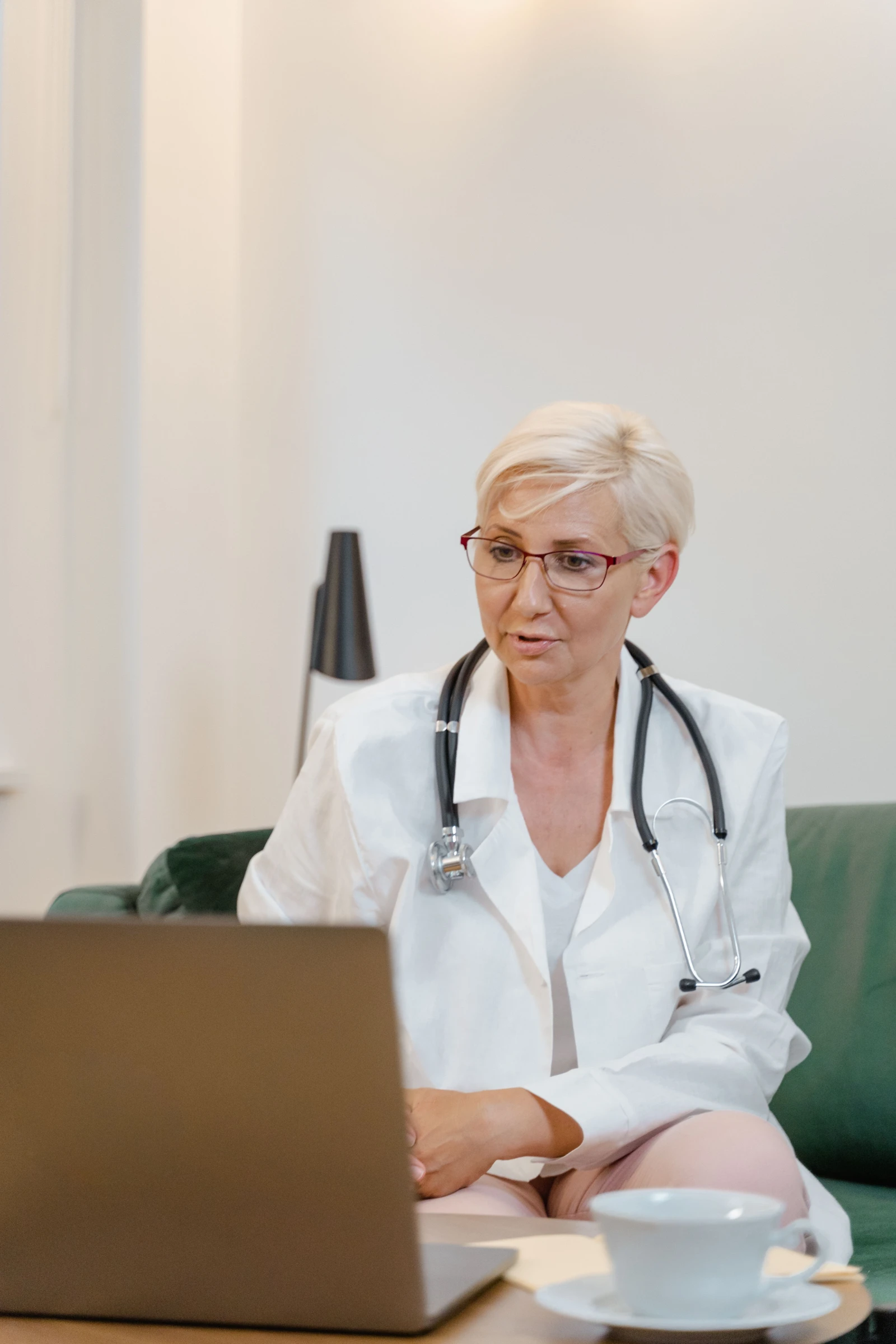 Eine ältere medizinische Fachkraft in einem Videoanruf mit einem Patienten, die ein Stethoskop und einen Laborkittel trägt